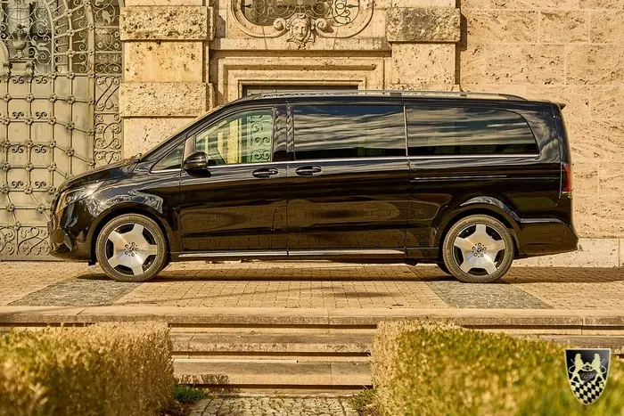 Kleinbus mieten München für 2 bis 20 Personen mit Premium und Luxus Bussen und Vans 7 Ein professioneller Chauffeur öffnet die Tür eines eleganten Mercedes Sprinter, der als komfortabler Kleinbus für Reisen und Transfers dient. Der Fahrer bietet einen erstklassigen Service, ideal für Gruppen und Veranstaltungen in München.